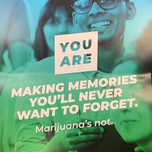 Colorful blue and green poster showing a photo of a smiling student and the text YOU ARE making memories you'll never want to forget