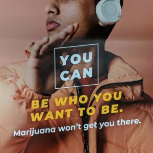 Colorful orange and blue poster with a photo of a male student with headphones on and the text YOU CAN be who you want to be