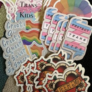 Colorful LGBTQ+ stickers featuring text like "Protect trans kids" and "Queer joy"