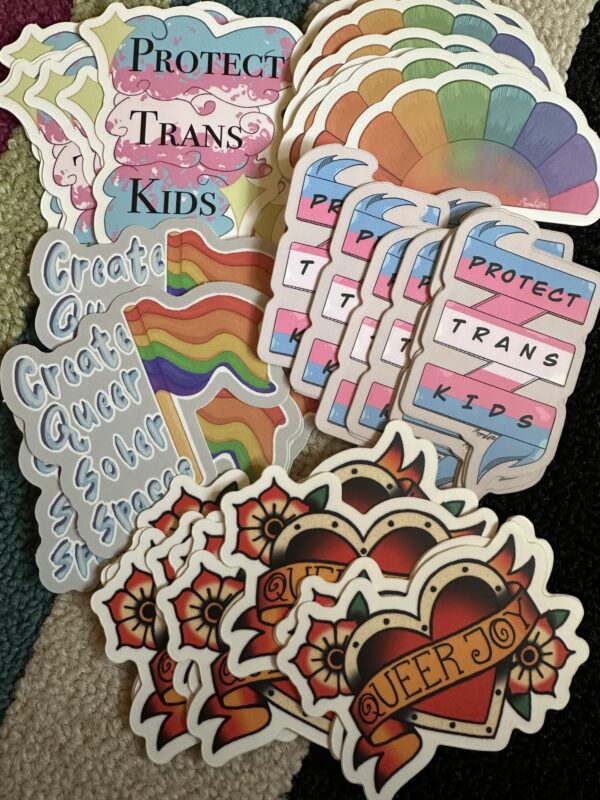 Colorful LGBTQ+ stickers featuring text like "Protect trans kids" and "Queer joy"